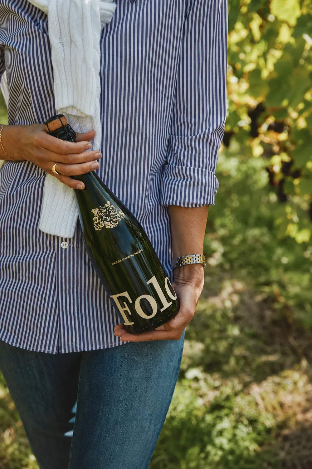A bottle of Folc sparkling rosé held in a vineyard