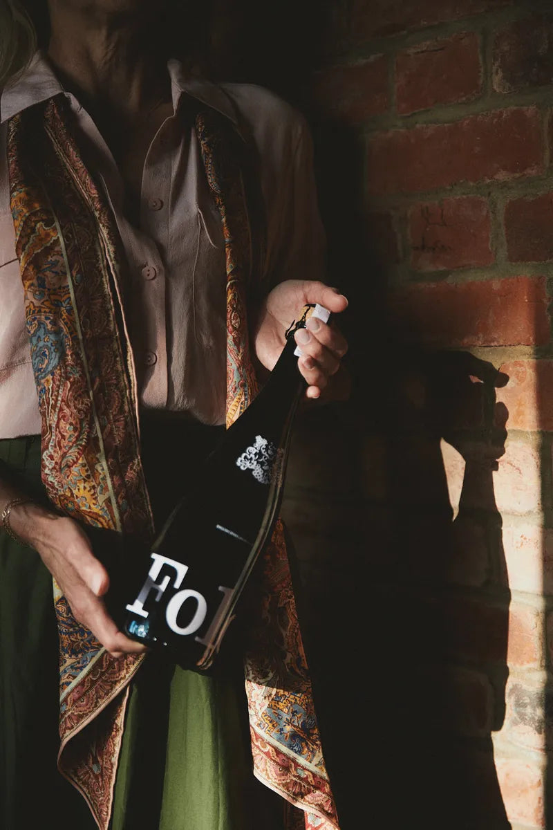 A bottle of Folc sparkling rosé held against a printed scarf