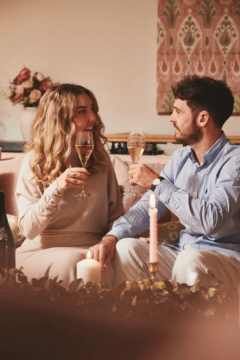 A couple toasting with Folc sparkling rosé by candlelight