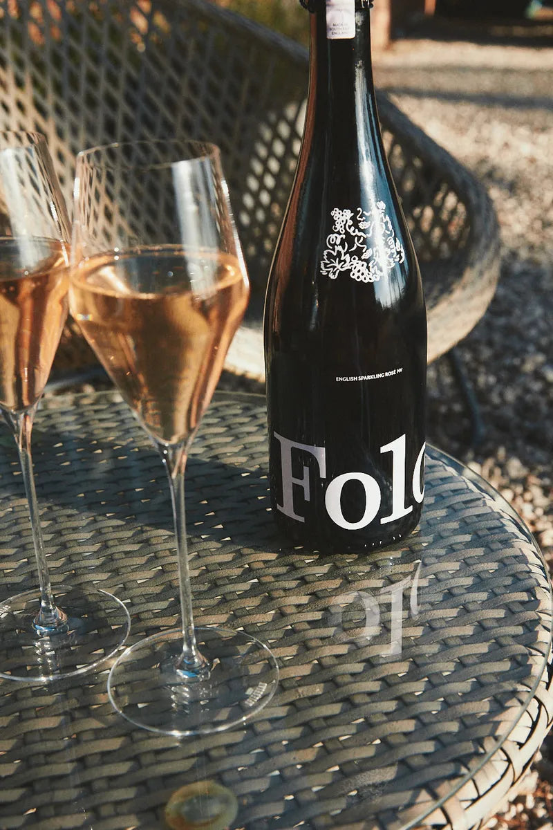 Two flutes of Folc sparkling rosé beside the bottle on a garden table