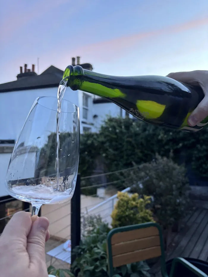 Pouring Folc sparkling rosé in a garden
