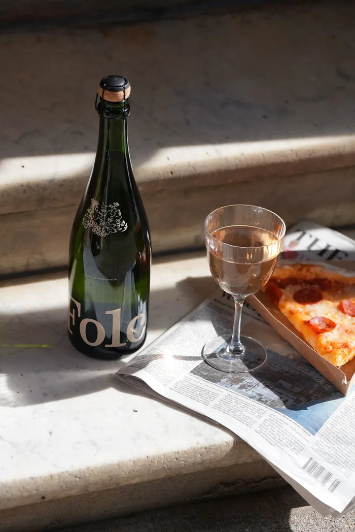 Folc sparkling rosé with a glass and a slice of pizza on sunny steps