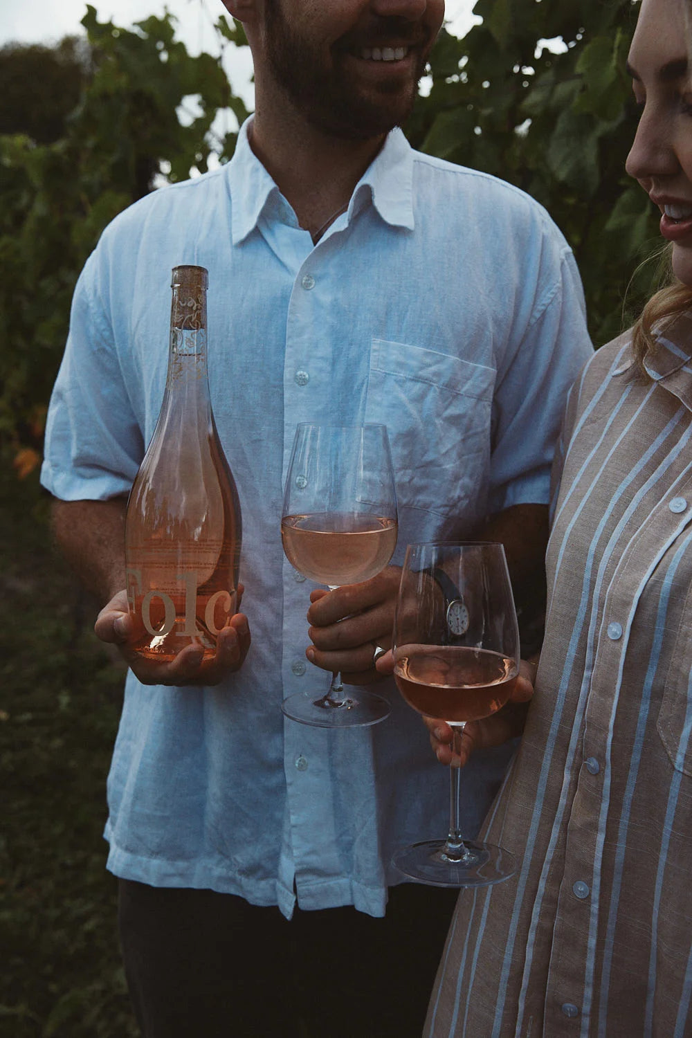 A couple in a vineyard with a bottle of Folc rosé