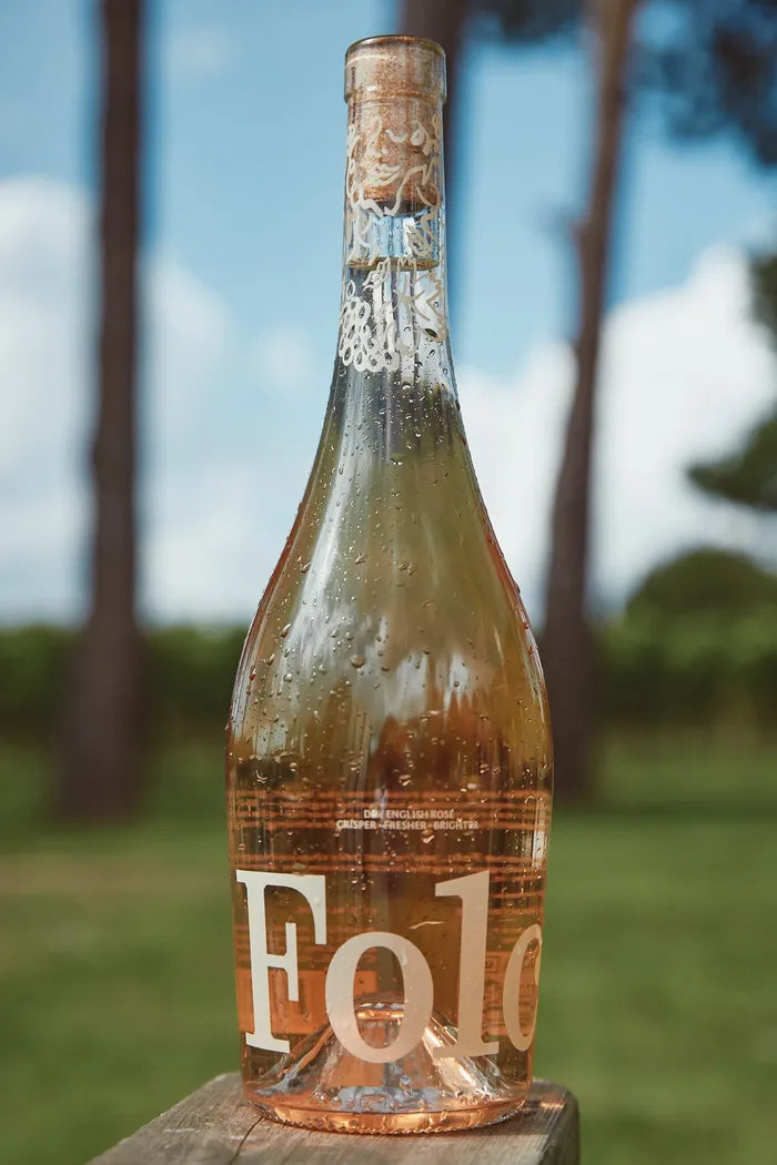 A bottle of Folc rosé on a wooden rail in a vineyard