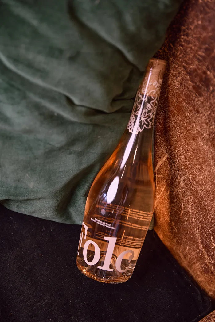 A bottle of Folc rosé on a green velvet sofa